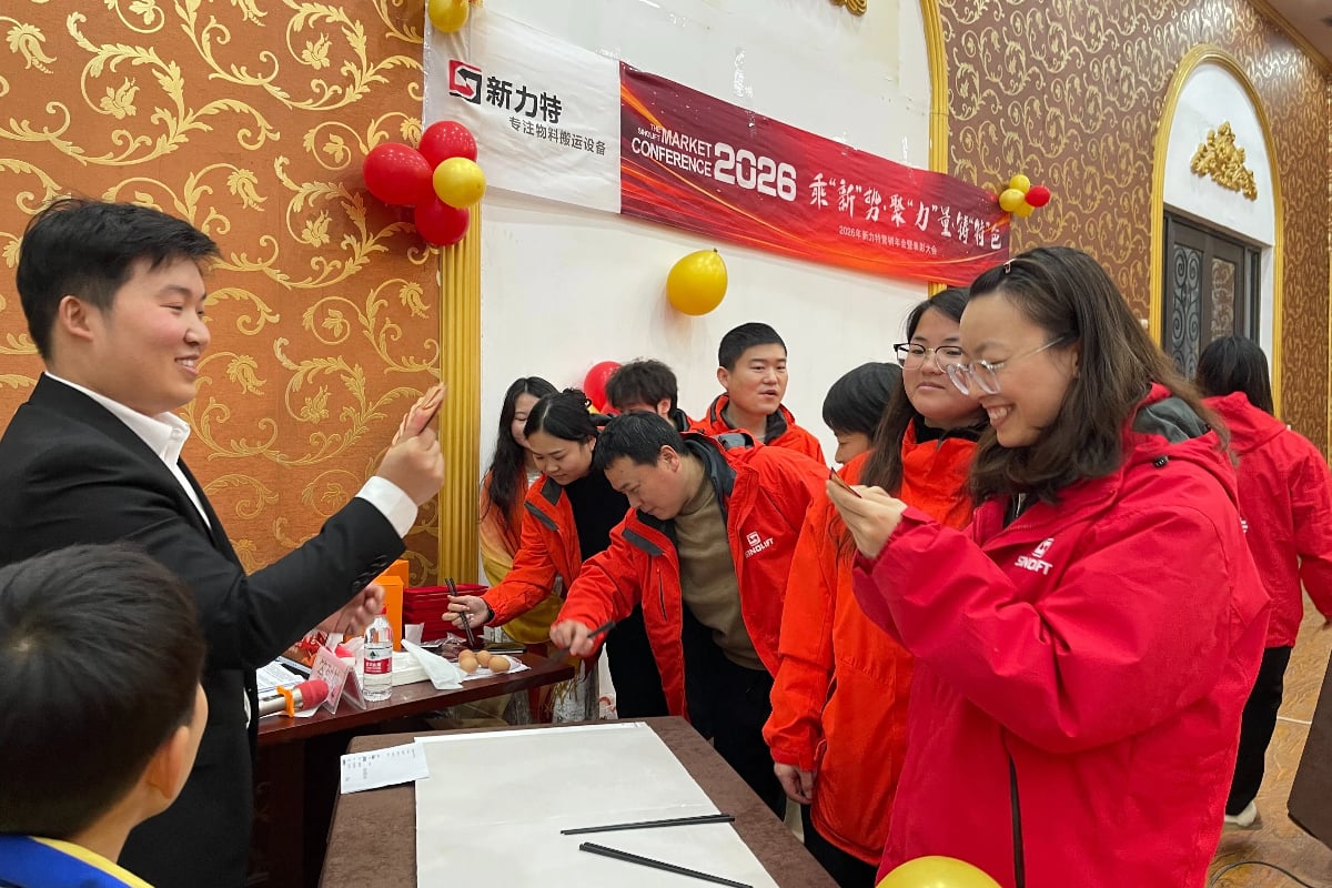 SINOLIFT employees cheering and holding hands in a large group photo, showcasing the company's strong team building spirit and unity at the coast.